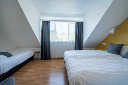 Twin hotel room with dark grey curtains and two single beds, Hótel Breiðdalsvík East Iceland