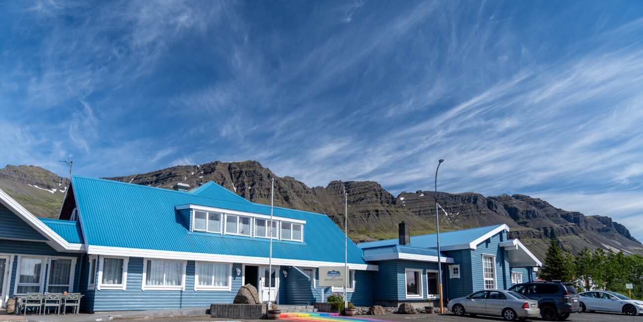 Exterior of Hótel Breiðdalsvík blue building with dramatic mountain backdrop, East Iceland