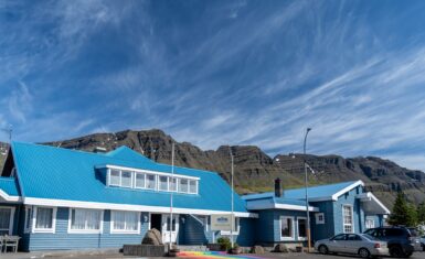 Exterior of Hótel Breiðdalsvík blue building with dramatic mountain backdrop, East Iceland